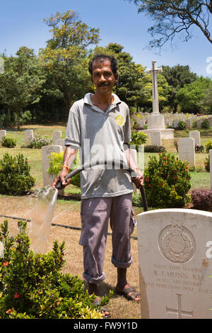 Sri Lanka, Trincomalee, Uppuveli, homme de guerre du Commonwealth, l'arrosage des fleurs au cimetière Banque D'Images