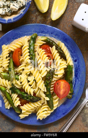 Asperges vertes cuites au four, tomate cerise et salade de pâtes rotini servi sur une assiette de fromage bleu et citron wegde sur le côté Banque D'Images