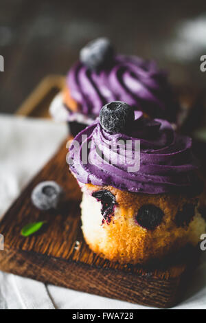 Blueberry cupcakes avec crème au beurre violet sur planche de bois, Close up. Clé faible, selective focus Banque D'Images