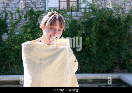 Young woman smiling, enveloppé dans une serviette après une baignade Banque D'Images