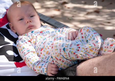 Angelic petit bébé garçon couché sur les jambes de son père. Banque D'Images