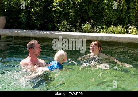 Famille en vacances à jouer dans une piscine Banque D'Images