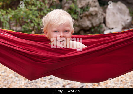 Close up portrait of a happy smiling boy dans un hamac rouge Banque D'Images