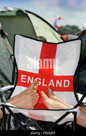 Revelers reste les pieds sur une chaise longue patriotique au festival de Glastonbury 2010, UK Somerset Pilton Banque D'Images