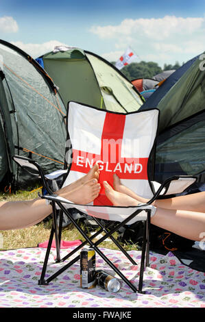 Revelers reste les pieds sur une chaise longue patriotique au festival de Glastonbury 2010, UK Somerset Pilton Banque D'Images