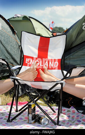 Revelers reste les pieds sur une chaise longue patriotique au festival de Glastonbury 2010, UK Somerset Pilton Banque D'Images