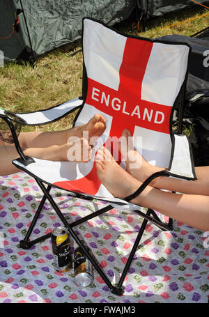 Revelers reste les pieds sur une chaise longue patriotique au festival de Glastonbury 2010, UK Somerset Pilton Banque D'Images