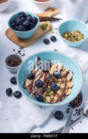 Sain et Délicieux bol de porridge avec des bleuets frais. les fèves de cacao et de bananes Banque D'Images