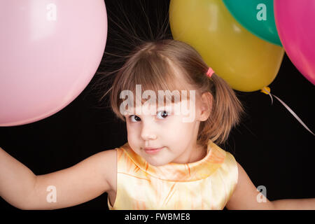 Studio portrait of smiling little Young blonde avec des ballons colorés Banque D'Images