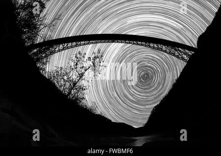 Le mouvement des étoiles dans le ciel gelé pendent au-dessous d'un écran géant sur le pont d'acier d'une gorge en noir et blanc, New River Gorge, West Virginia. Banque D'Images