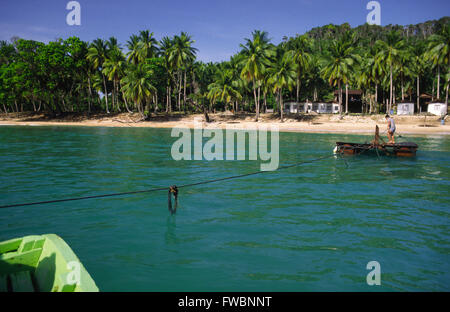 Sibu island au large de la Malaisie et les décideurs ont besoin de vacances à bord d'un petit radeau à partir de leur bateau et sont ensuite tiré sur le radeau par corde à travers l'île. L'île a un style chalet / hut resort et est typique des petites îles de la région offrant calme solitaire se casse sur la magnifique bordée de palmiers des plages de sable. Banque D'Images