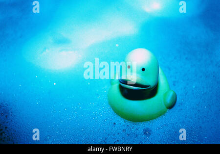 Un petit canard en caoutchouc entre les bulles et flottant dans un bain de mousse, dans ce très stylisé et coloré image prise avec l'amélioration des techniques de photgraphic bleu spécial. Banque D'Images