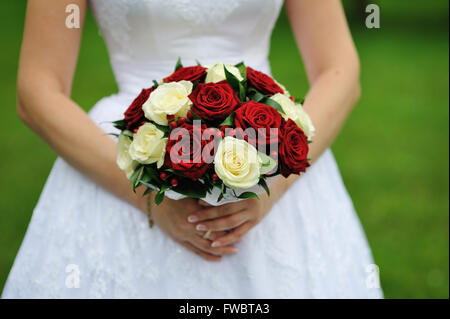 Bride holding bouquet de fleur de mariage de roses rouges et blanches Banque D'Images