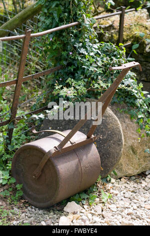 Un rouleau de jardin métallique traditionnelle se trouve dans le coin d'un jardin anglais. Banque D'Images