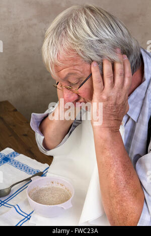 Vieil homme solitaire détestant son porridge petit déjeuner le matin Banque D'Images