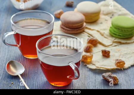 Deux tasses en verre de thé noir et de macarons colorés Banque D'Images