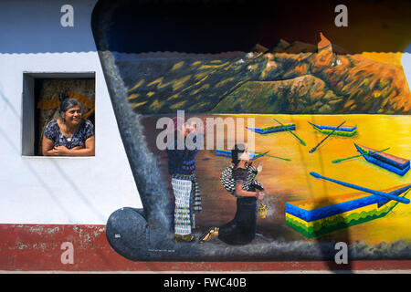 Femme dans un local à côté de Windows d'un mur haletant dans San Juan La Laguna, Solola, Guatemala. Peinture art maya traditionnel Sant Banque D'Images