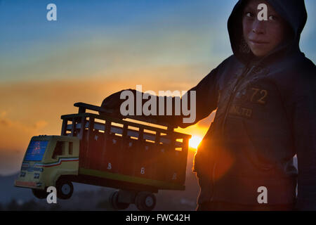 Coucher du soleil dans les montagnes près de Chimaltenango, Guatemala. Un enfant jouant avec un camion jouet. Banque D'Images