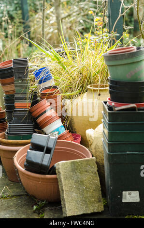 Des piles de plastique et pots de terre cuite à l'extérieur dans un jardin. Banque D'Images