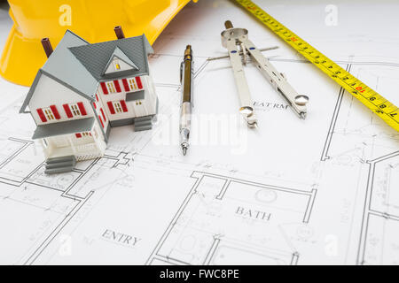 Maison modèle, ruban à mesurer, Casque, crayon et compas reposant sur des plans de maison. Banque D'Images