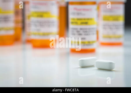 Gamme de flacons de médicaments et de grandes Non-Proprietary Pills on Reflective Surface avec fond gris. Banque D'Images