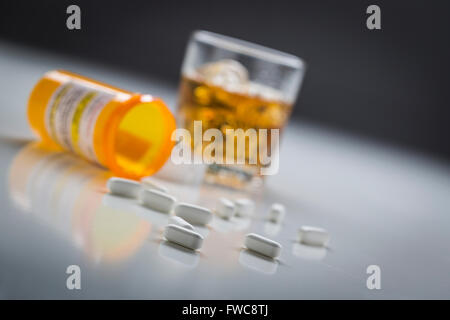 Plusieurs médicaments déversés par bouteille tombé près de verre d'alcool. Banque D'Images