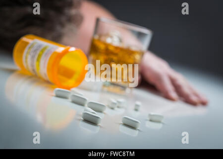 Homme inconscient face vers le bas derrière dispersés aux médicaments sur ordonnance et verre d'alcool. Banque D'Images