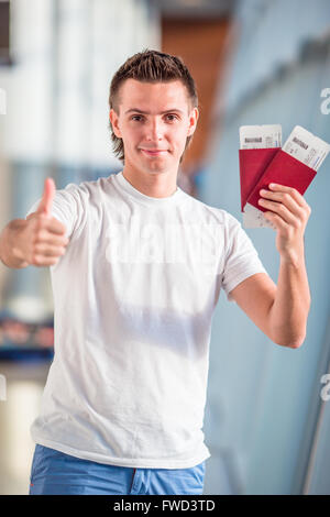 Jeune homme avec les passeports et cartes d'embarquement à l'aéroport Banque D'Images