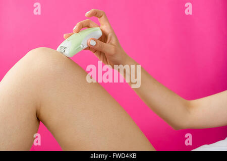 Femme epilates sa jambe avec un appareil d'épilation électrique Banque D'Images