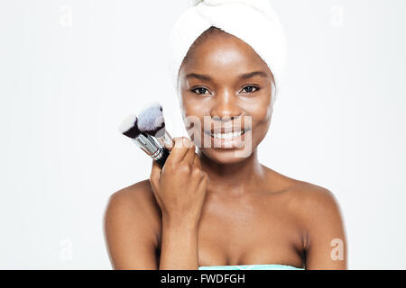 Smiling afro american woman holding makeup brushes isolé sur fond blanc Banque D'Images