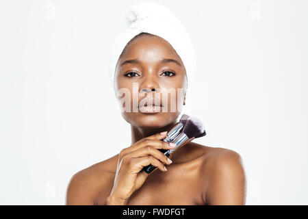 Femme Jeune avec towel on head holding makeup brushes isolé sur fond blanc Banque D'Images