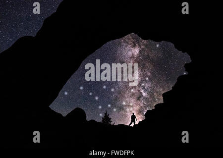 Un homme debout contre la Voie Lactée, fenêtre nord à Arches National Park, Utah. Banque D'Images