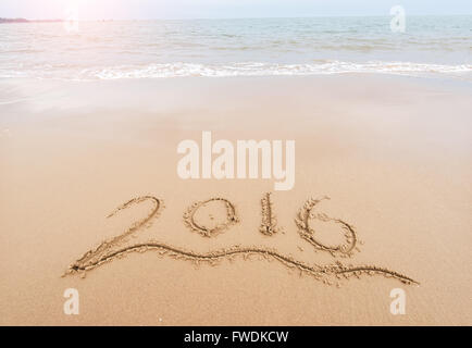 Année 2016 écrit à la main sur le sable blanc en face de la mer Banque D'Images