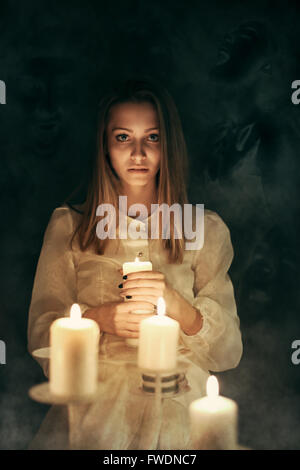 Jeune femme avec des bougies entouré par les fantômes . Et effrayant Halloween Banque D'Images