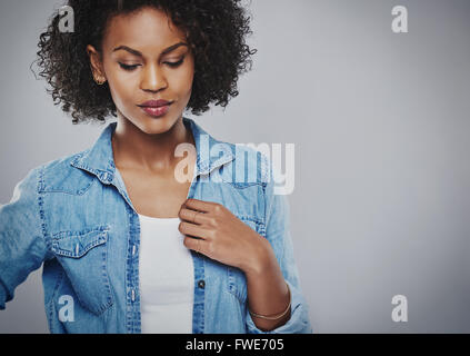 Thoughtful young African American Woman wearing une veste en jean décontracté debout avec les yeux baissés regardant le Banque D'Images