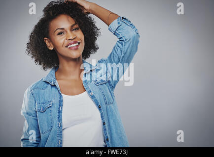 Vive heureux young African American Woman avec les cheveux bouclés debout avec sa main à sa tête regardant la caméra avec un lov Banque D'Images