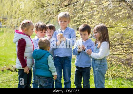 Groupe d'enfants d'âge préscolaire, les amis et les frères et sœurs, jouant dans le parc avec des petits poussins, le printemps au cours de la journée Banque D'Images