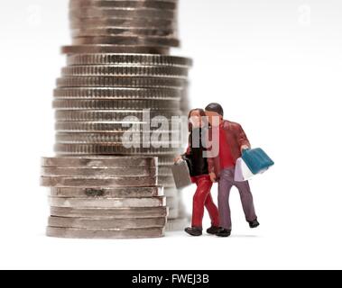 Un petit couple carrying shopping bags walking par des piles de pièces. Banque D'Images