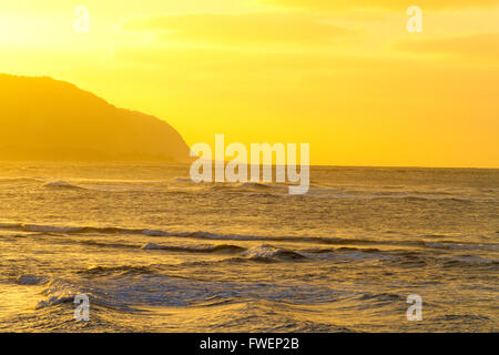 Le ciel devient jaune et ciel voilé au cours de ce coucher de soleil sur la côte nord d'Oahu à Hawaii. La photo montre un rocher outc Banque D'Images