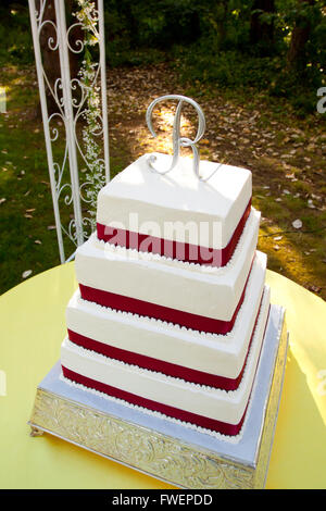 Un Carre Rouge Et Blanc Gateau De Mariage Avec Plusieurs Niveaux Et La Lettre R Sur Le Haut Se Trouve A L Exterieur Sur Une Table Jaune Pour Un Mariage Loisir Photo Stock