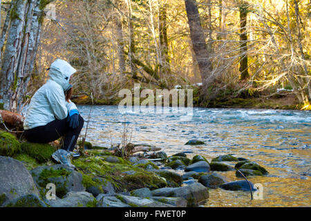 Une femme prend un randonneur reste et donne sur l'eau de la rivière McKenzie dans l'Oregon. Banque D'Images