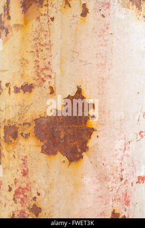 La peinture s'écaille ce rusty weathered pole montrant certains tons de blanc rose orange et rouge. Banque D'Images