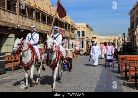 Scène de rue animée avec les policiers à cheval habillés de façon traditionnelle et shoppers, Souq Waqif, Doha, Qatar, Moyen-Orient Banque D'Images