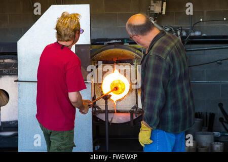 Deux hommes travaillent dur pour créer une pièce d'art unique de verre en fusion. Ils sont dans un studio de verre soufflé dans l'Oregon. Banque D'Images