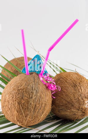 Noix de coco fraîche cocktails avec parasols placés sur des feuilles de cocotier Banque D'Images