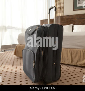 Grande valise à roulettes bleu debout sur le plancher dans la chambre d'hôtel. Style de voyage concept. Image carré Banque D'Images