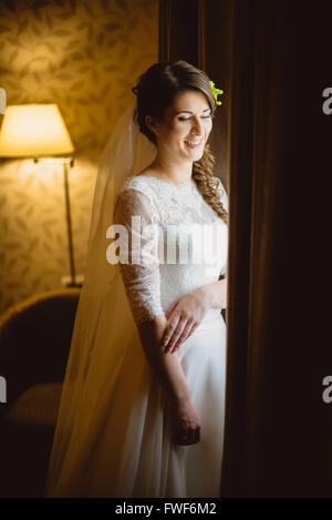 Mariée en robe blanche, debout près de window Banque D'Images