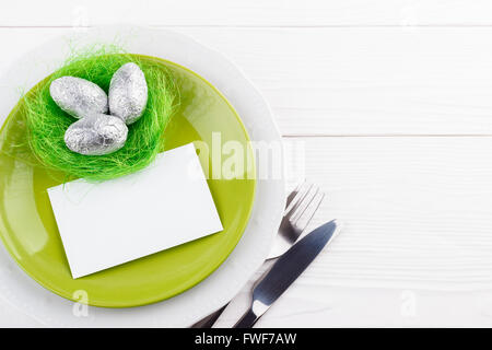 Table de pâques printemps avec l'argenterie des œufs en chocolat dans un nid, copy space Banque D'Images