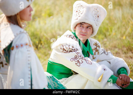 L'homme sur l'herbe en vêtements traditionnels regarde sa femme bien-aimée Banque D'Images