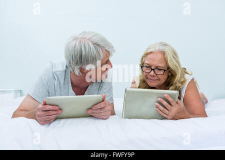 Senior couple talking lors de l'utilisation de tablettes numériques on bed Banque D'Images